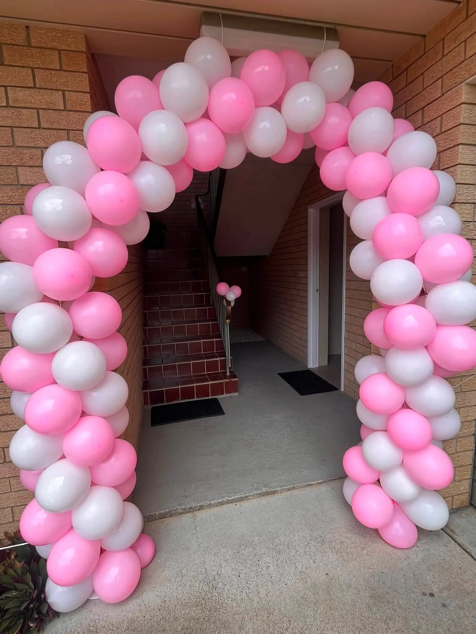 Pink, white and pastel balloon arch built around a front entrance