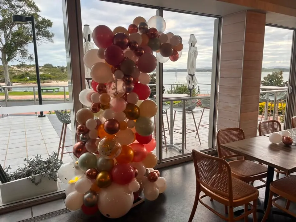 Copper, cream and green balloon column beside a waterfront venue window