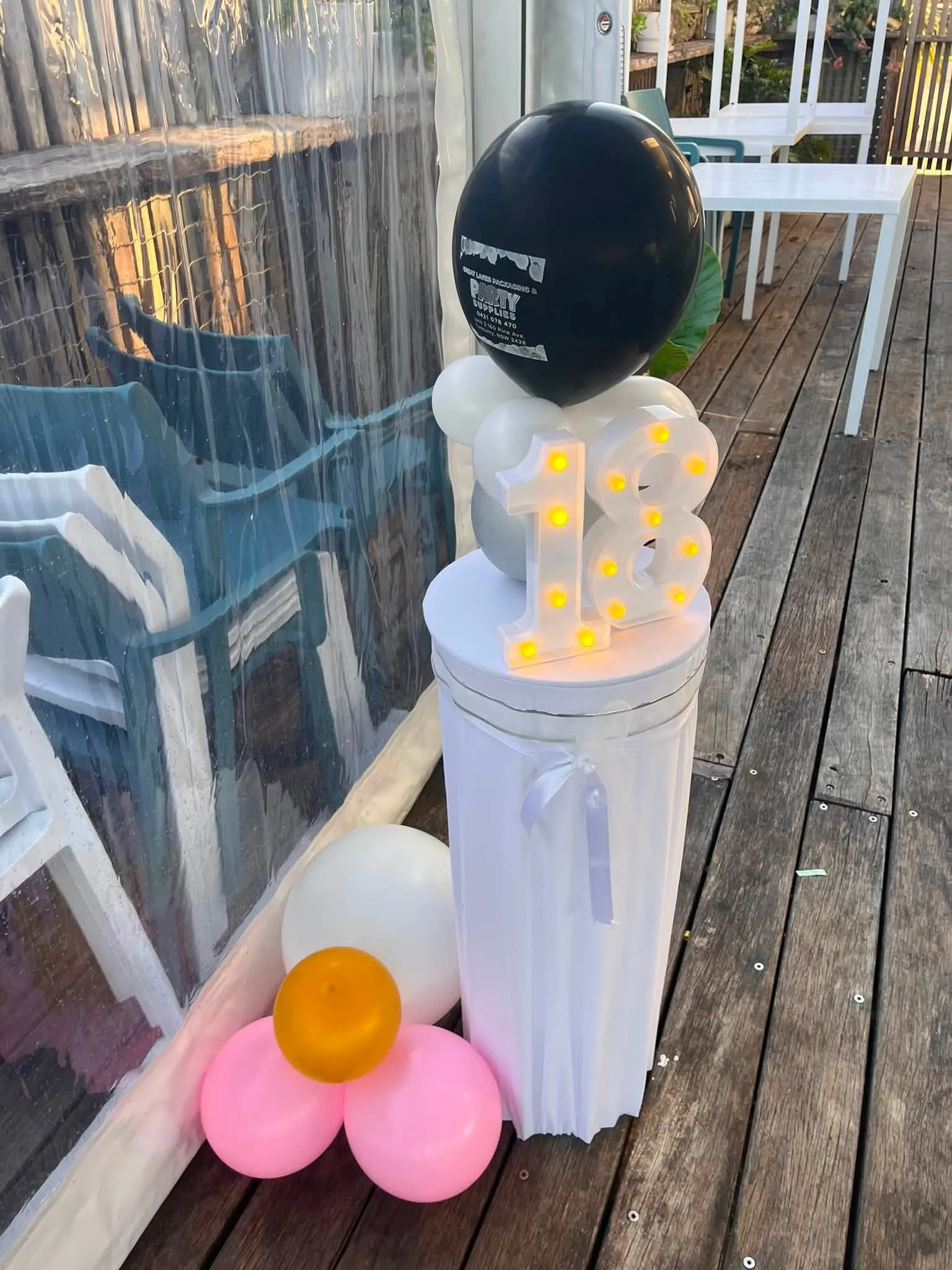 Weighted balloon centrepiece with a black topper and daisy detail on an outdoor table