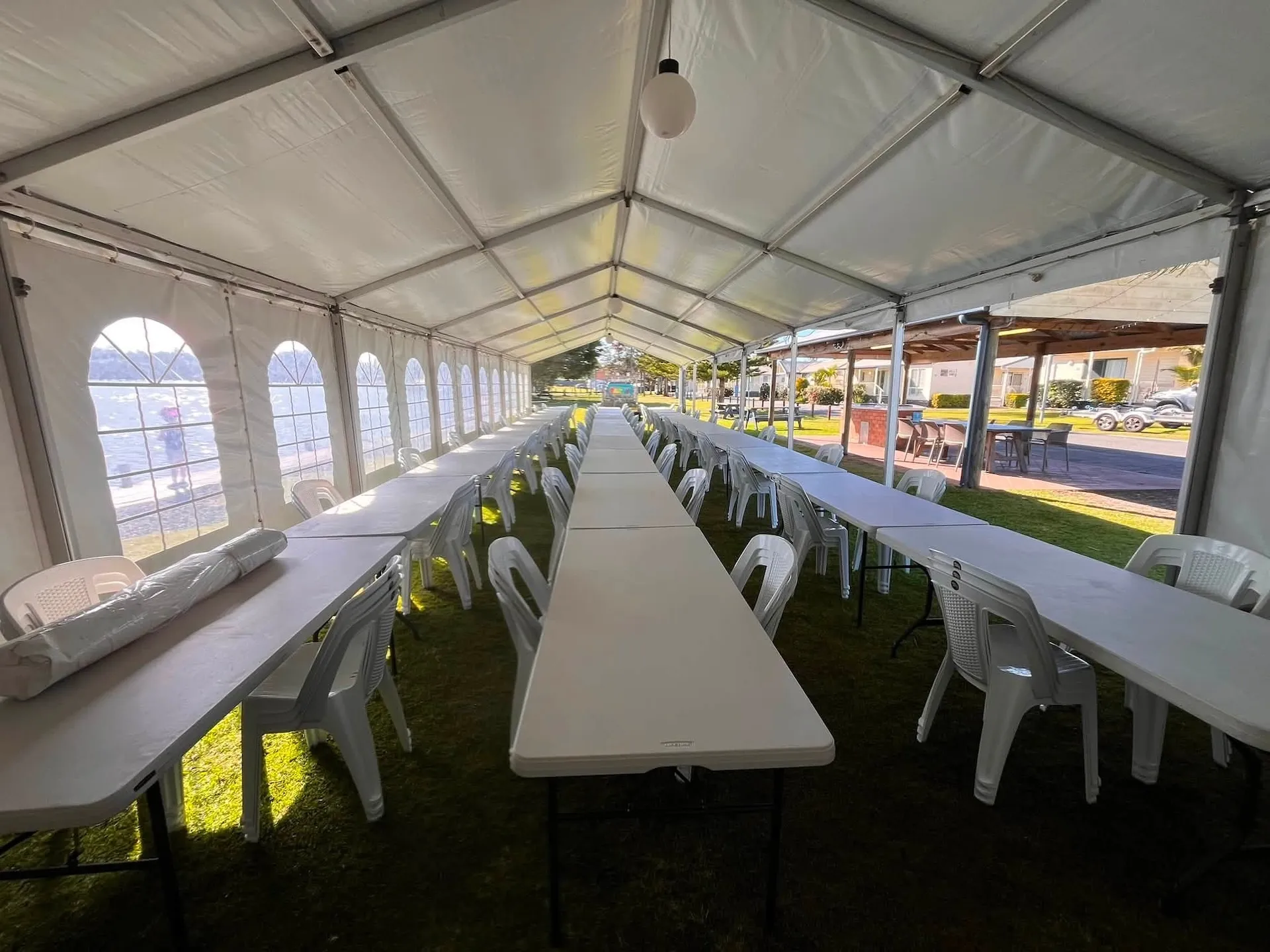 Function space set up with long trestle tables and white chairs for a seated function