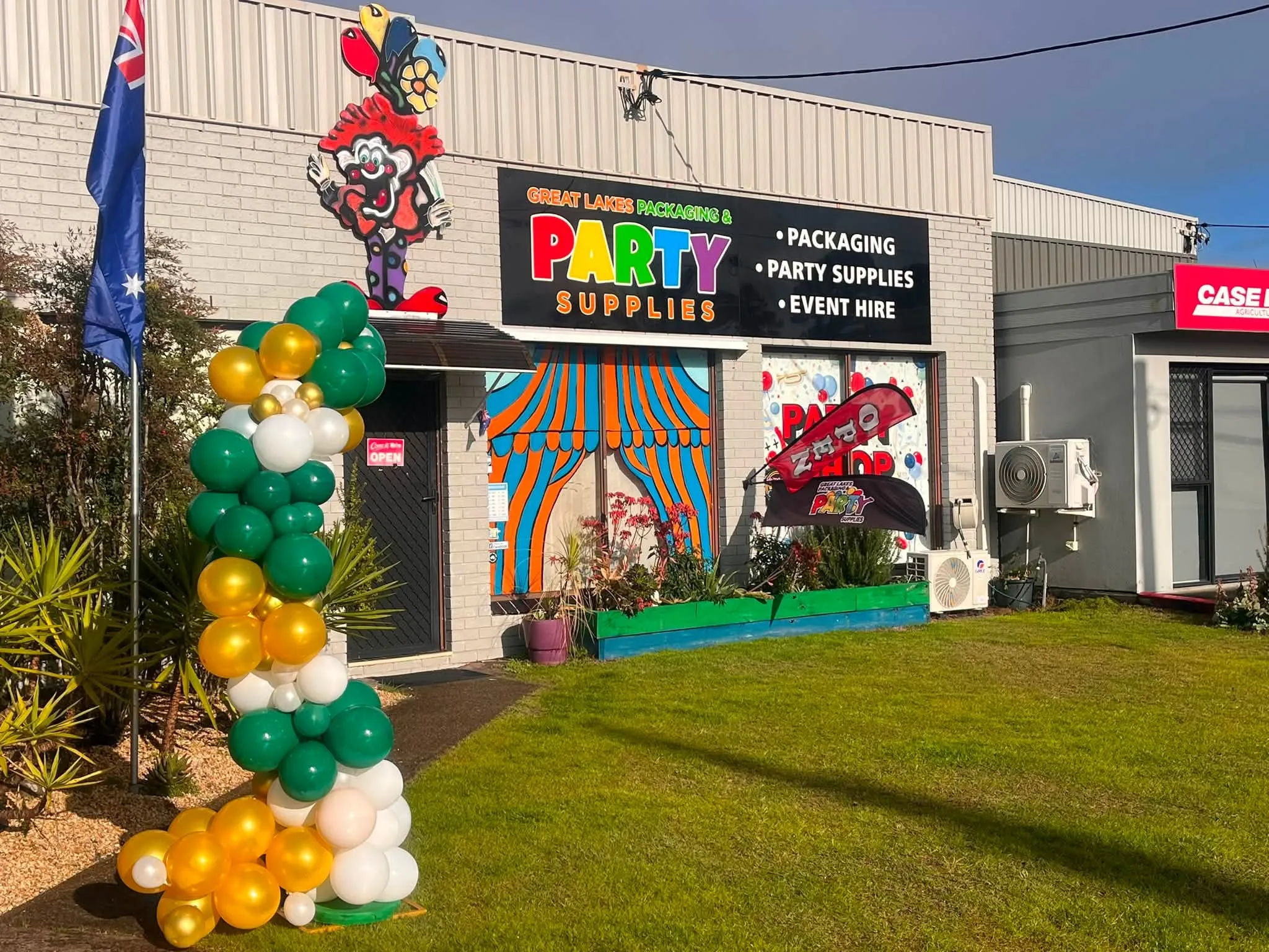 Great Lakes Packaging & Party Supplies shopfront in Tuncurry with a green, gold and white balloon column beside the door