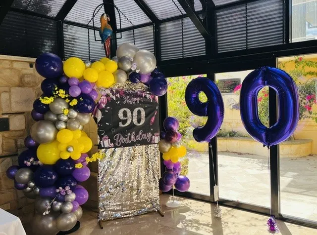 90th birthday party setup with purple and gold balloon garland and number balloons